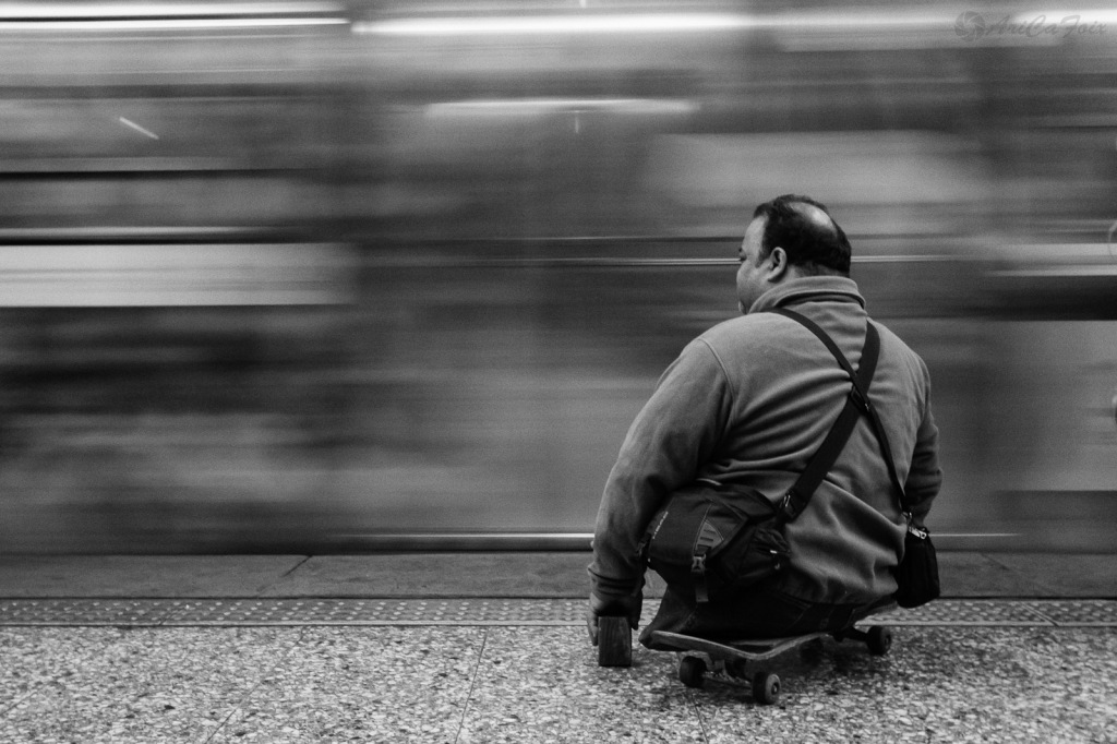 Un hombre sin piernas espera la detención del Metro, que pasa velozmente frente a él.